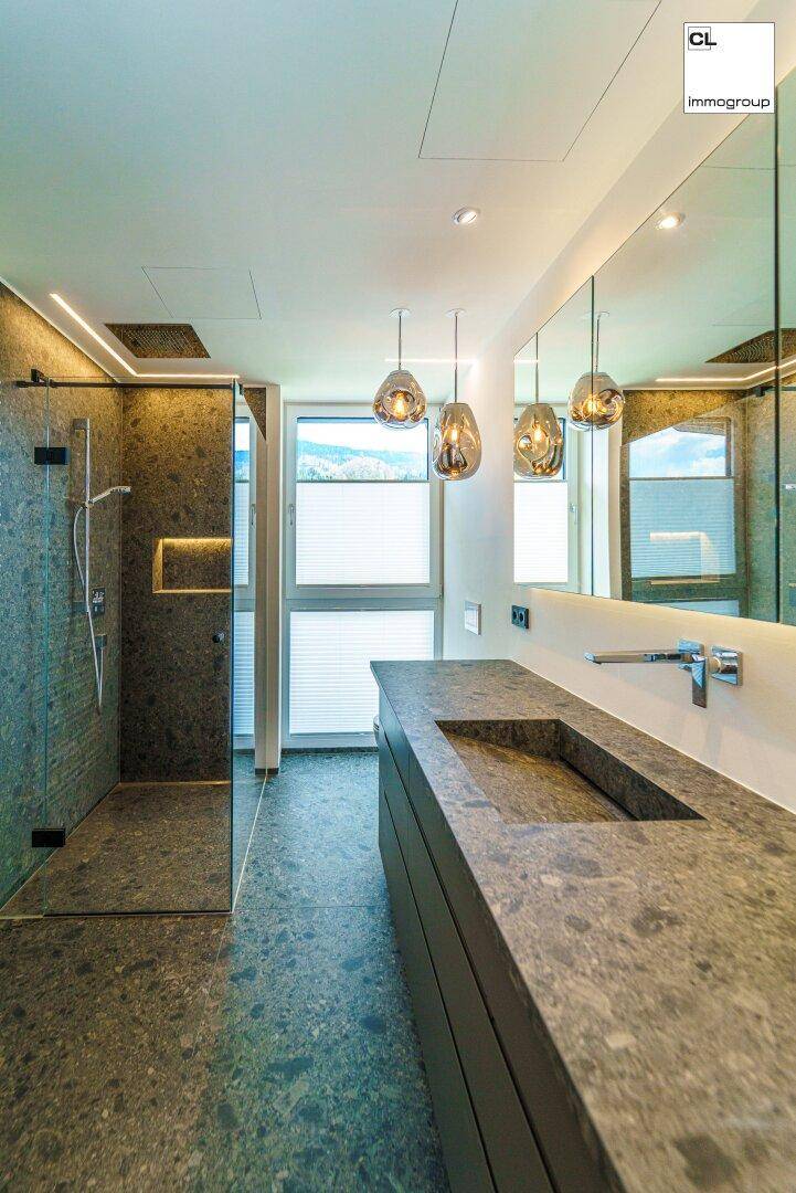 Modernes Badezimmer mit großformatigen Fliesen, begehbarer Dusche und Fenster für Tageslicht.