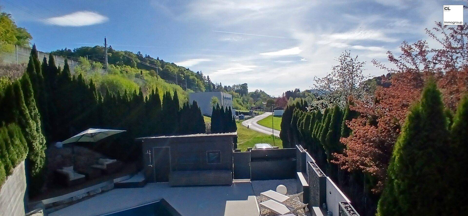 Panoramablick auf das Anwesen mit Pool, Garten und der umliegenden grünen Landschaft.