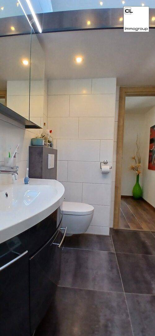 Modernes Gäste-WC mit Wand-WC, Waschbecken und großem Spiegel.