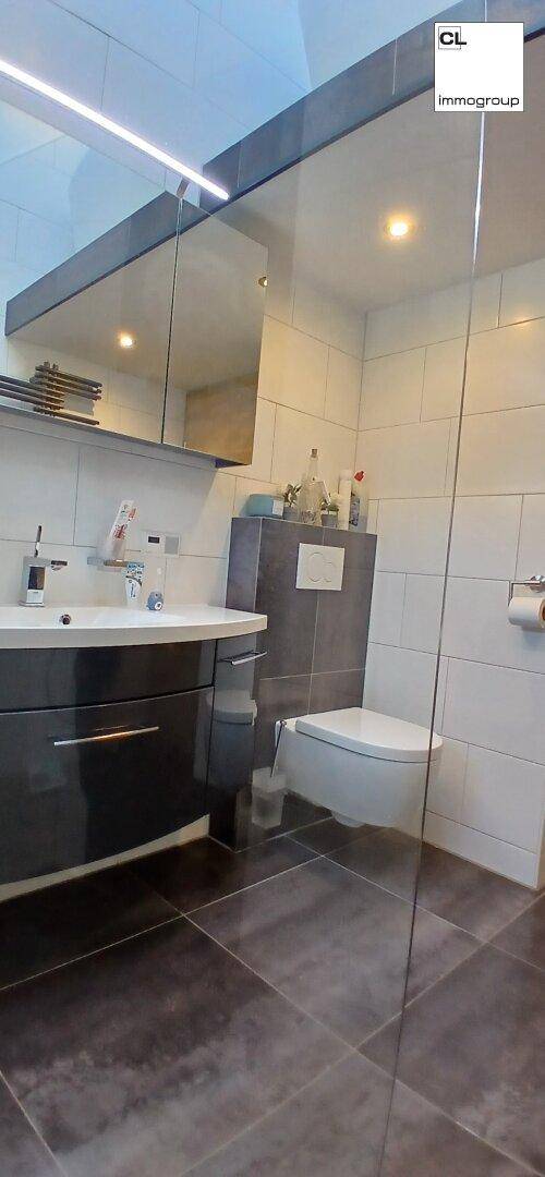 Helles Gäste-WC mit modernen Fliesen, wandhängendem WC und elegantem Waschbecken.