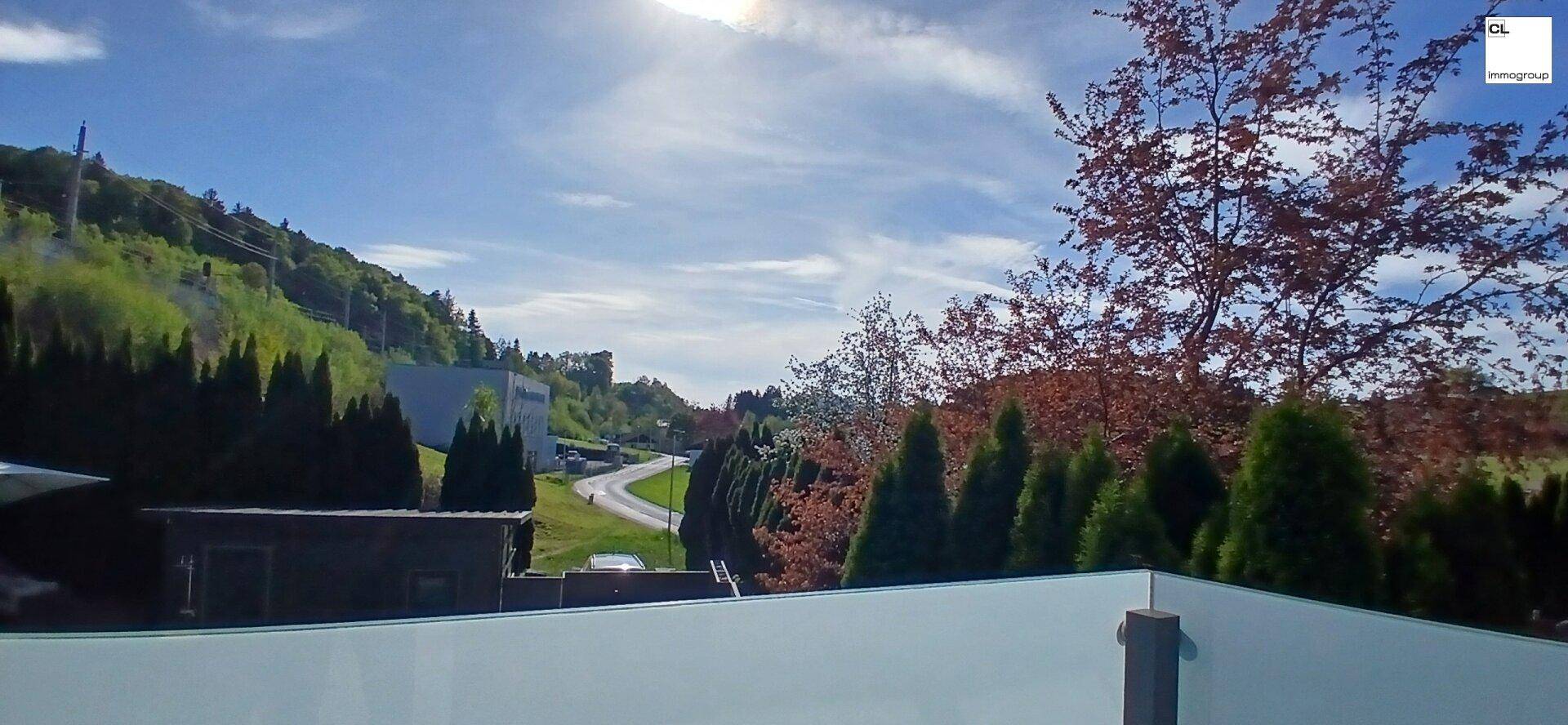 Weitläufiger Ausblick von einem Balkon auf die grüne Umgebung und die Landschaft.