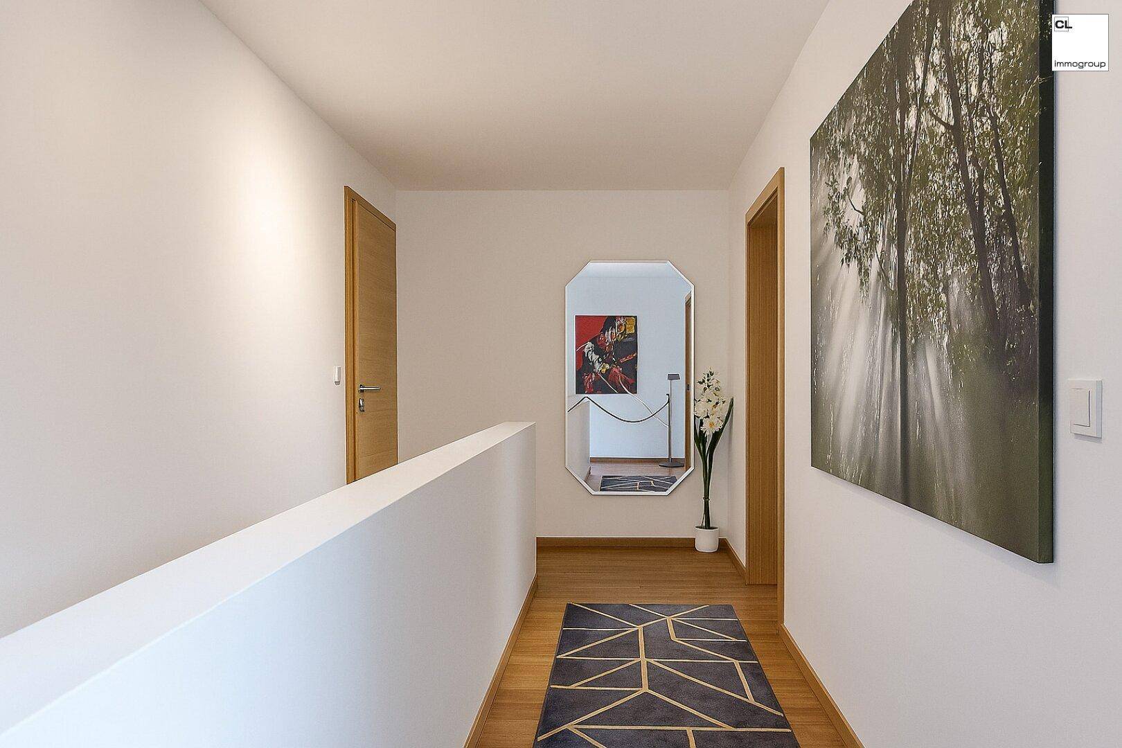 Heller Flur mit Holzfußboden, modernem Teppich und dekorativem Spiegel.