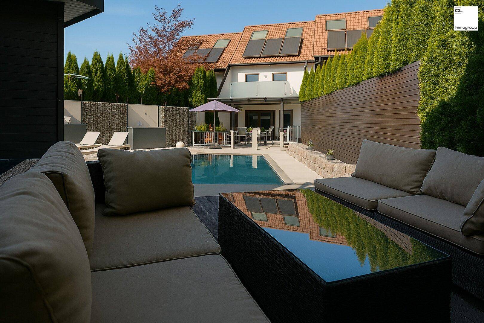 Gemütliche Lounge-Ecke im Garten mit Blick auf den Pool und das Haus.