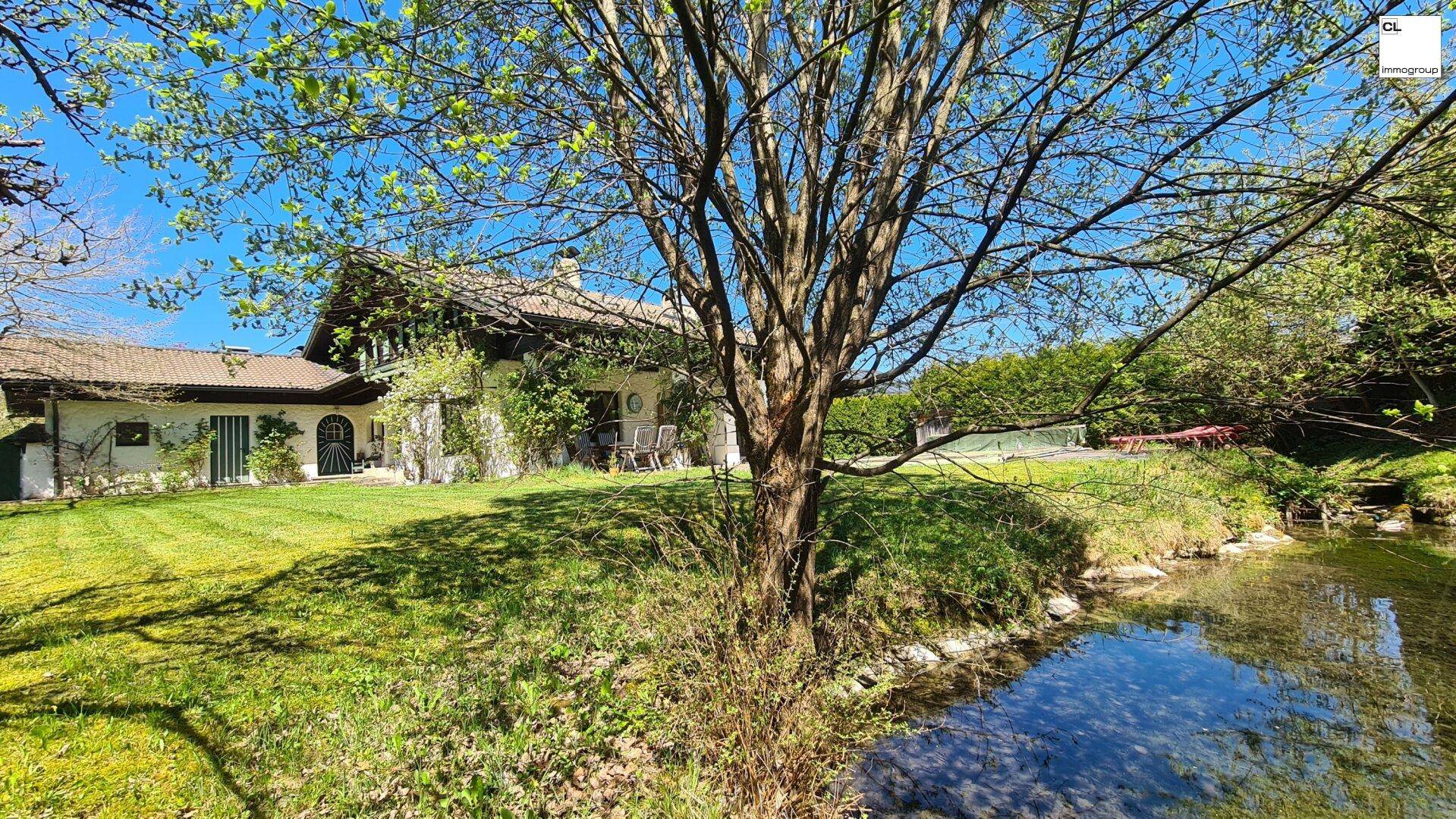 Weitläufiger Gartenbereich mit einem kleinen Teich und dem traditionellen Haus im Hintergrund.