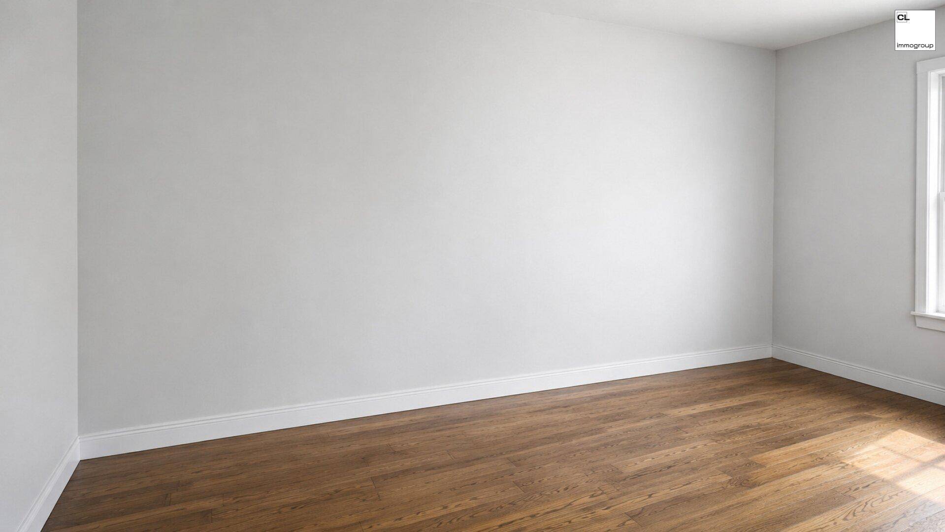 Heller Raum mit weißen Wänden und Holzfußboden, durch ein Fenster fällt Sonnenlicht auf den Boden.