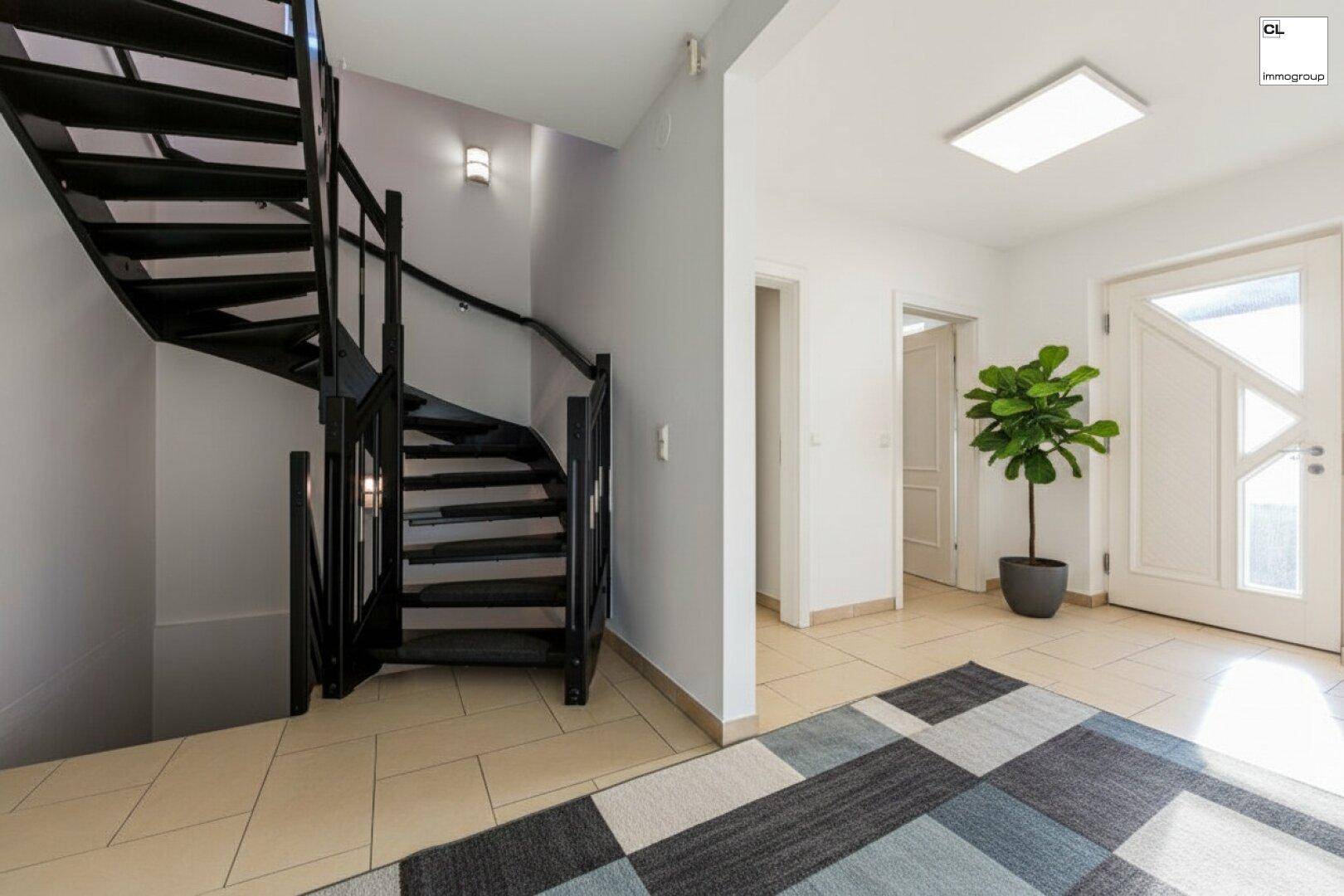 Heller Eingangsbereich mit Fliesenboden, moderner Wendeltreppe und viel Tageslicht.
