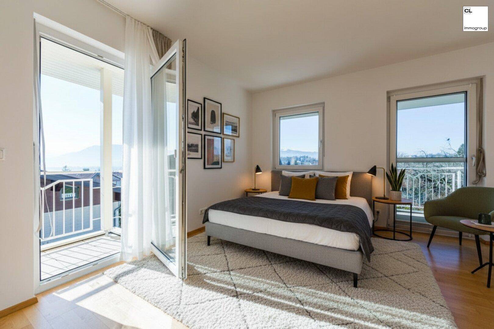 Helles Schlafzimmer mit Holzboden, Balkonzugang und weitem Blick auf die Landschaft.