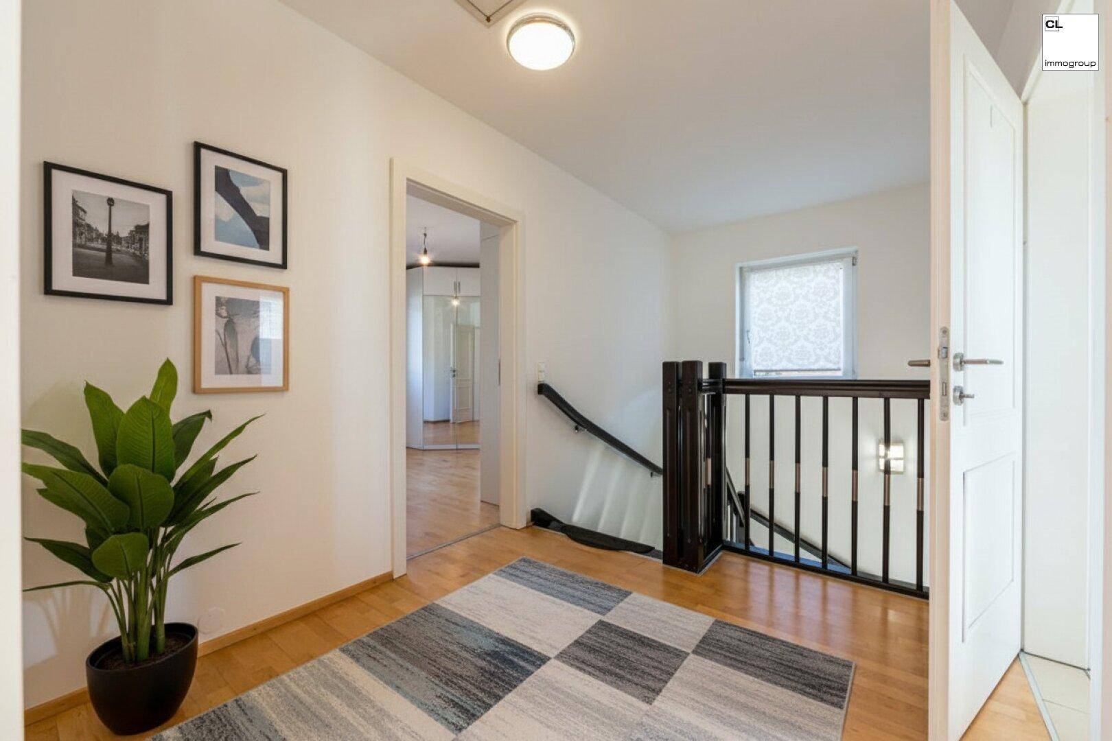 Oberer Flur mit Holzparkett, moderner Einrichtung und Blick auf die Treppe.