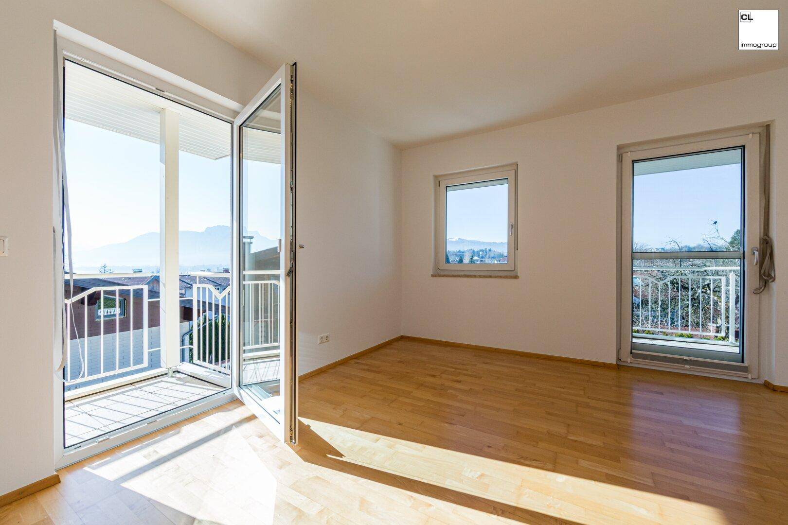Geräumiges Schlafzimmer mit Holzboden, großen Fenstern und direktem Zugang zum Balkon.