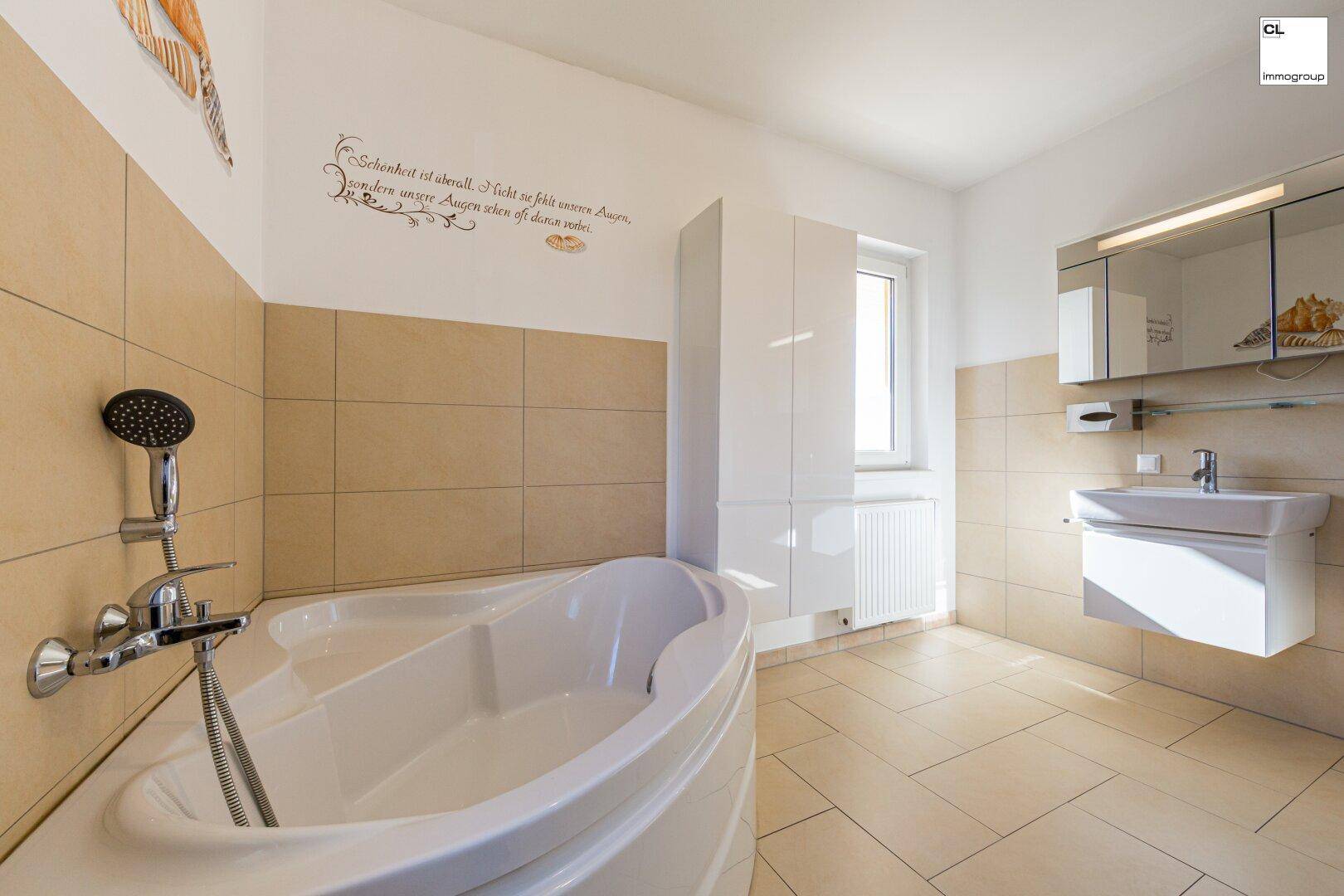 Helles Badezimmer mit Eckbadewanne, Einzelwaschbecken, Spiegelschrank und Fenster.