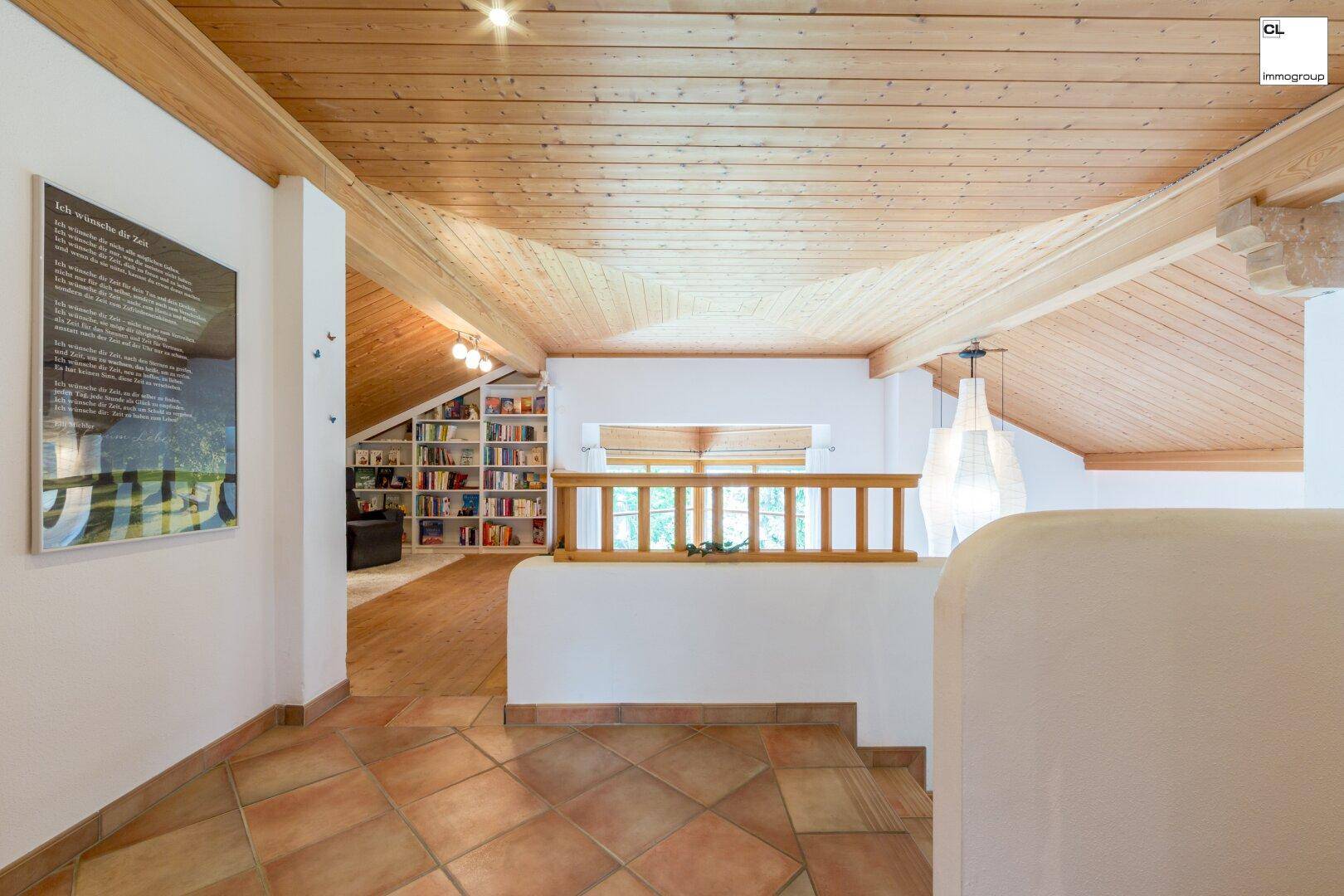 Heller Flur im Obergeschoss mit Holzdecke, Terrakottafliesen und Blick in einen Lesebereich.