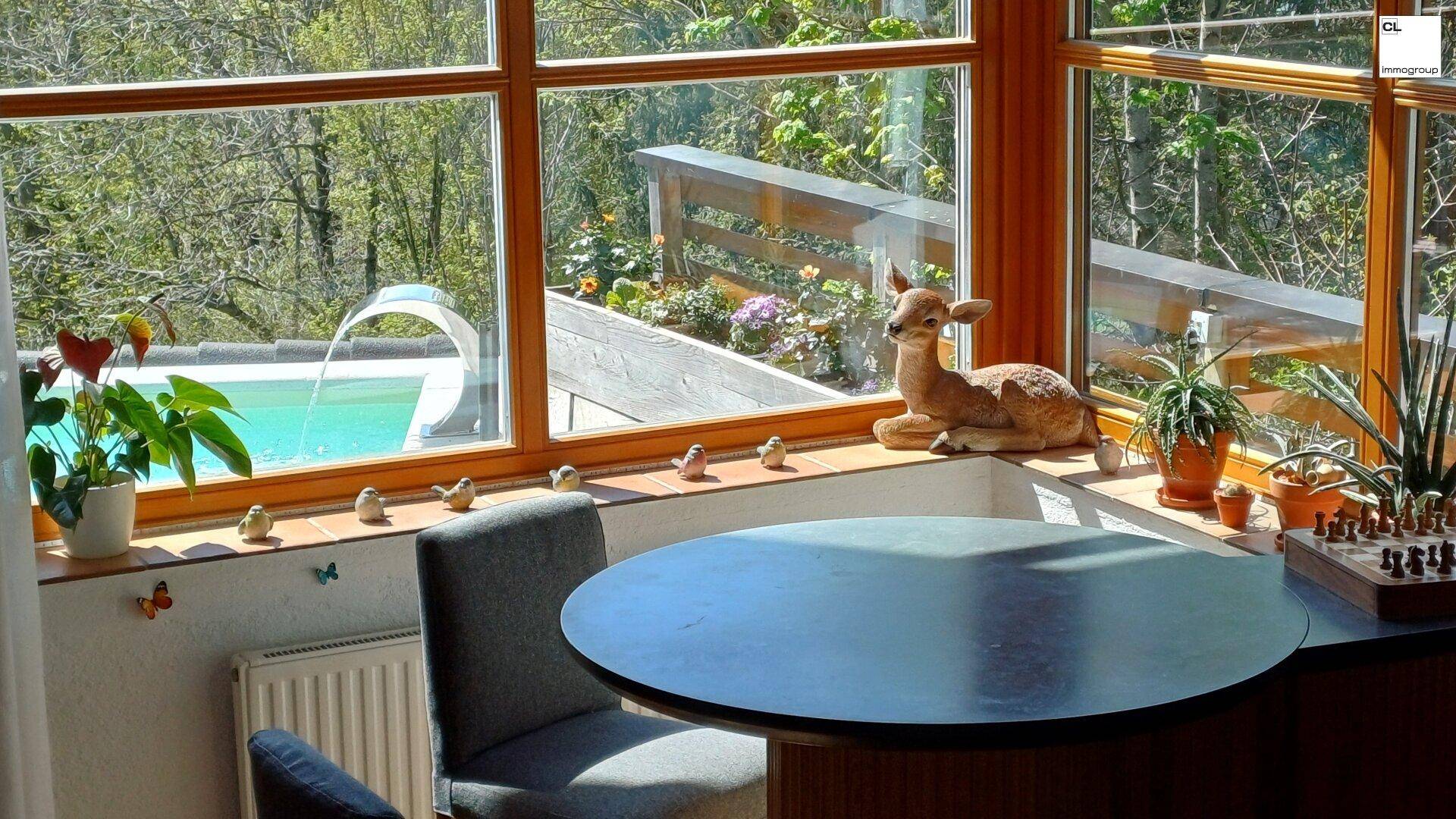 Gemütlicher Essbereich mit Rundtisch und großen Fenstern, die einen Blick auf den Pool bieten.