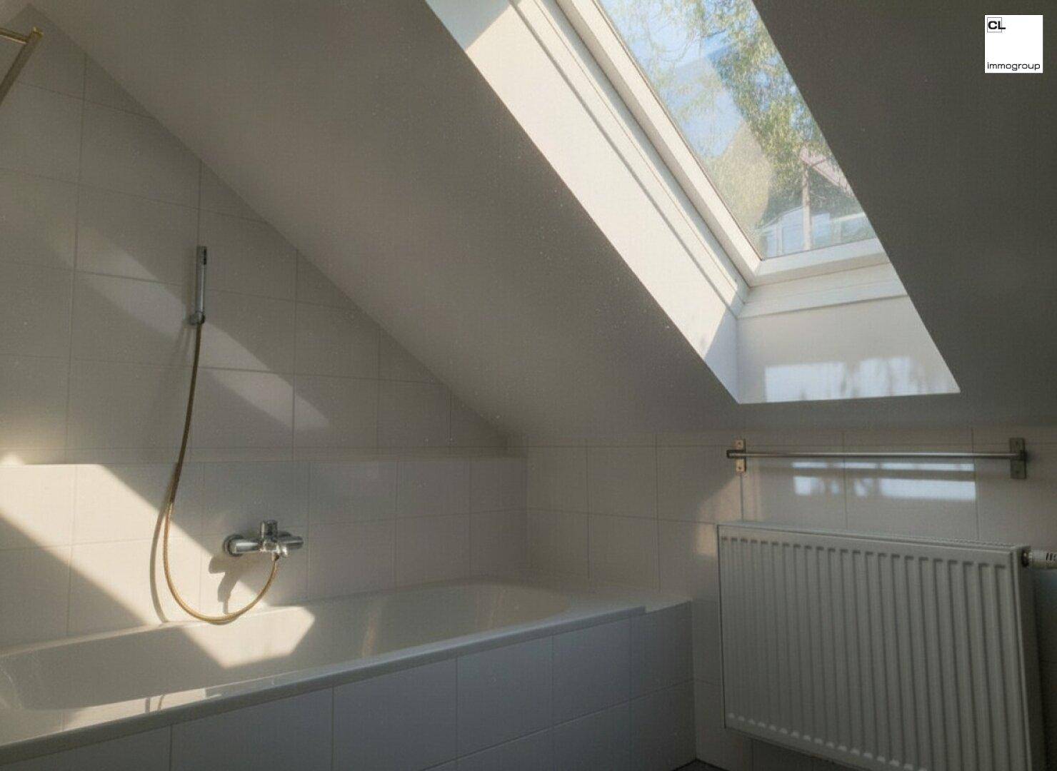 Badezimmer mit Badewanne, gefliesten Wänden, Heizkörper und einem Dachfenster, das viel Licht spendet.