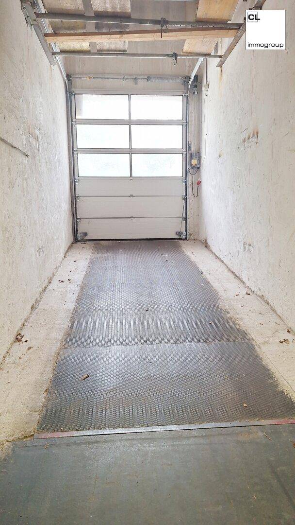 Einfahrt zu einer Garage oder Laderampe mit einem großen Rolltor und rutschfestem Bodenbelag.
