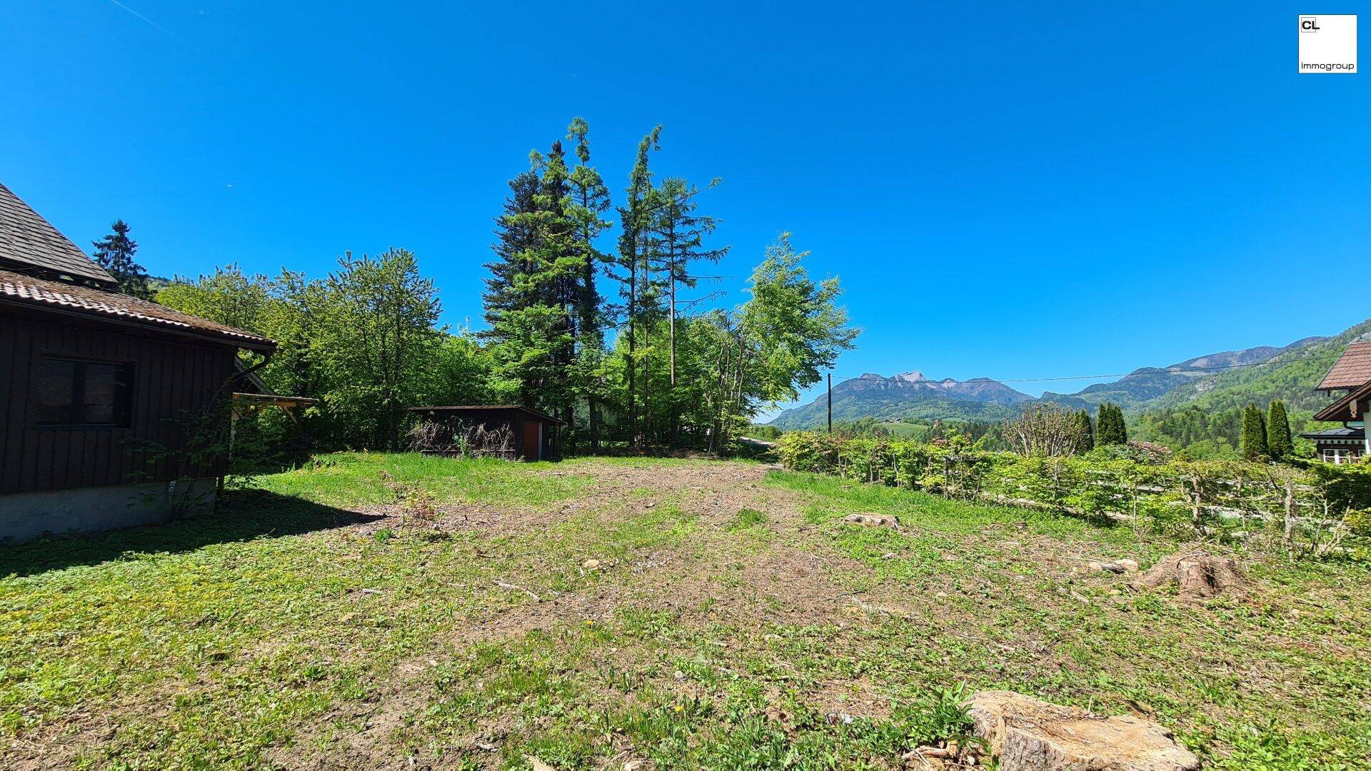 Grünes Grundstück mit Baumbestand und Blick auf die Berge, ideal für Naturliebhaber.