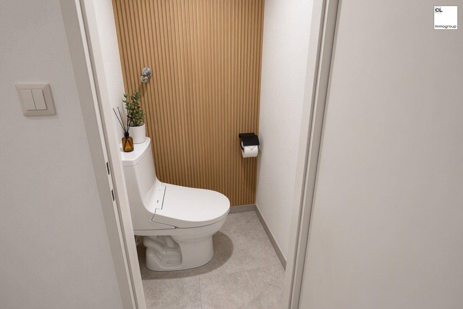 Separates WC mit moderner Toilette und dekorativer Holzlamellenwand für eine warme Atmosphäre.