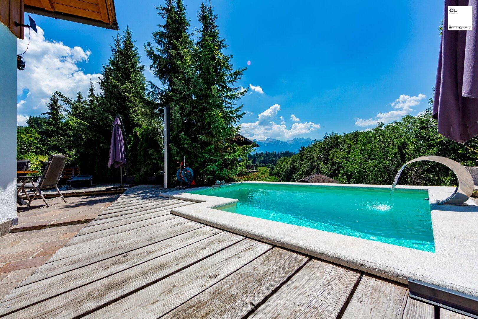 Holzterrasse mit integriertem Pool und Blick auf die grüne Landschaft unter blauem Himmel.