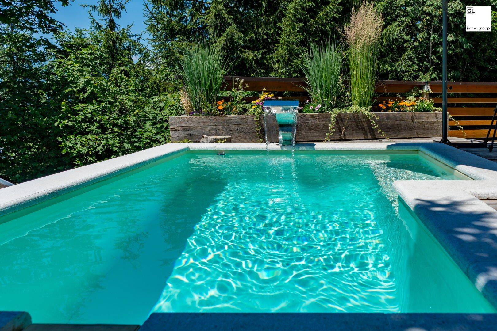 Kleiner Pool mit Wasserspiel, umgeben von üppiger Vegetation und Holzverkleidung.