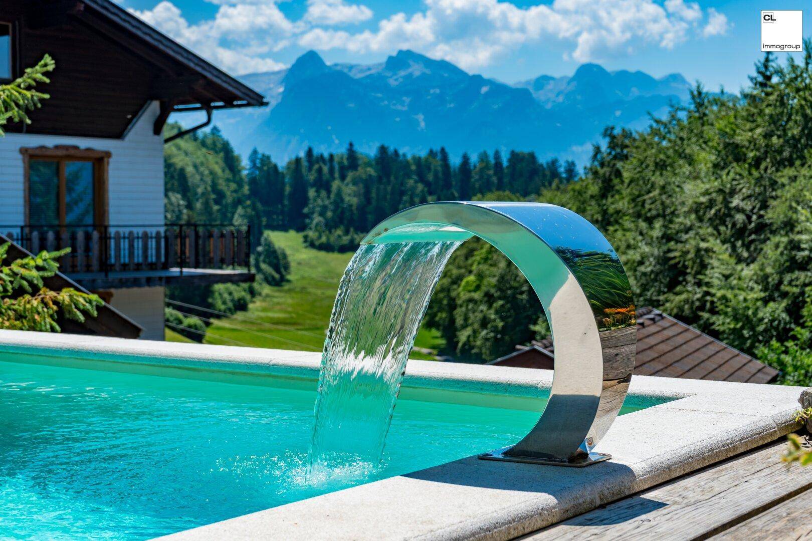 Pool mit modernem Wasserspiel und atemberaubendem Blick auf die umliegende Berglandschaft.