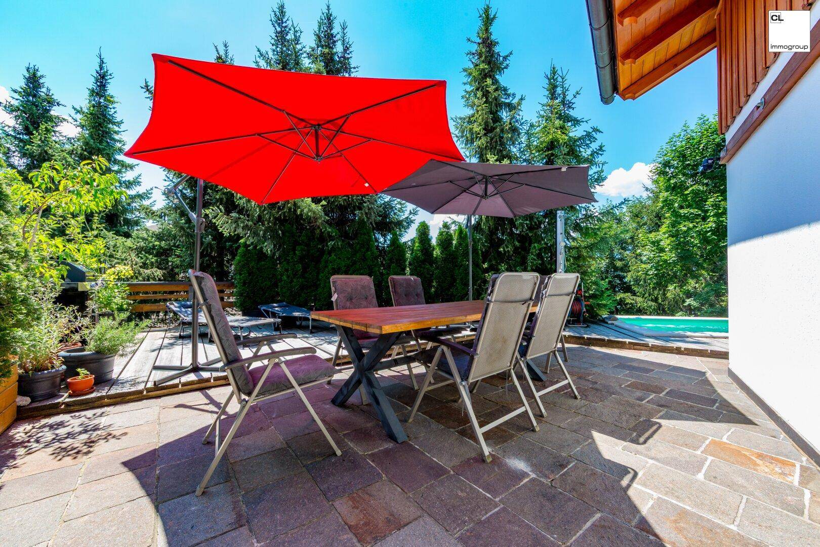 Gemütlicher Essbereich auf der Terrasse mit Sonnenschirmen und Blick auf die grüne Umgebung.