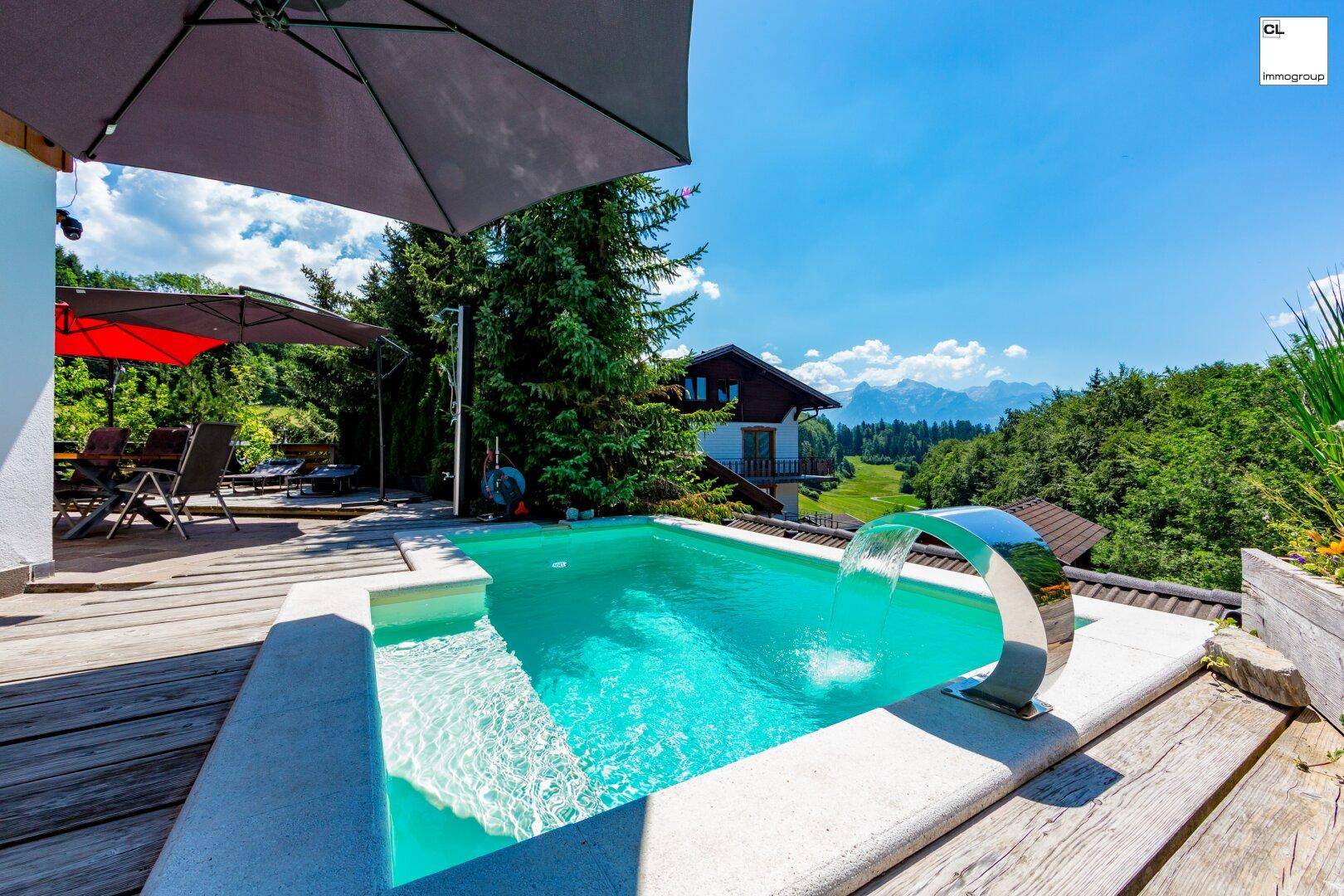 Poolbereich auf der Holzterrasse mit Wasserspiel und weitem Blick auf die Landschaft.