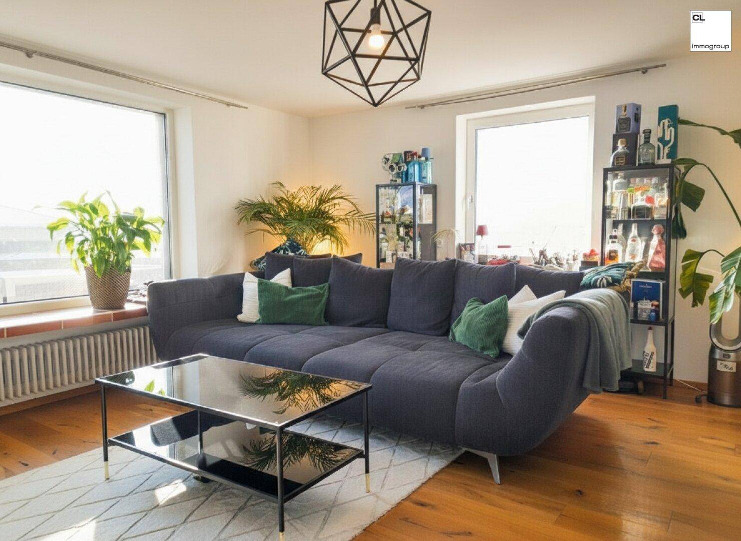 Helles Wohnzimmer mit großem Ecksofa, elegantem Couchtisch und viel Tageslicht durch die Fenster.