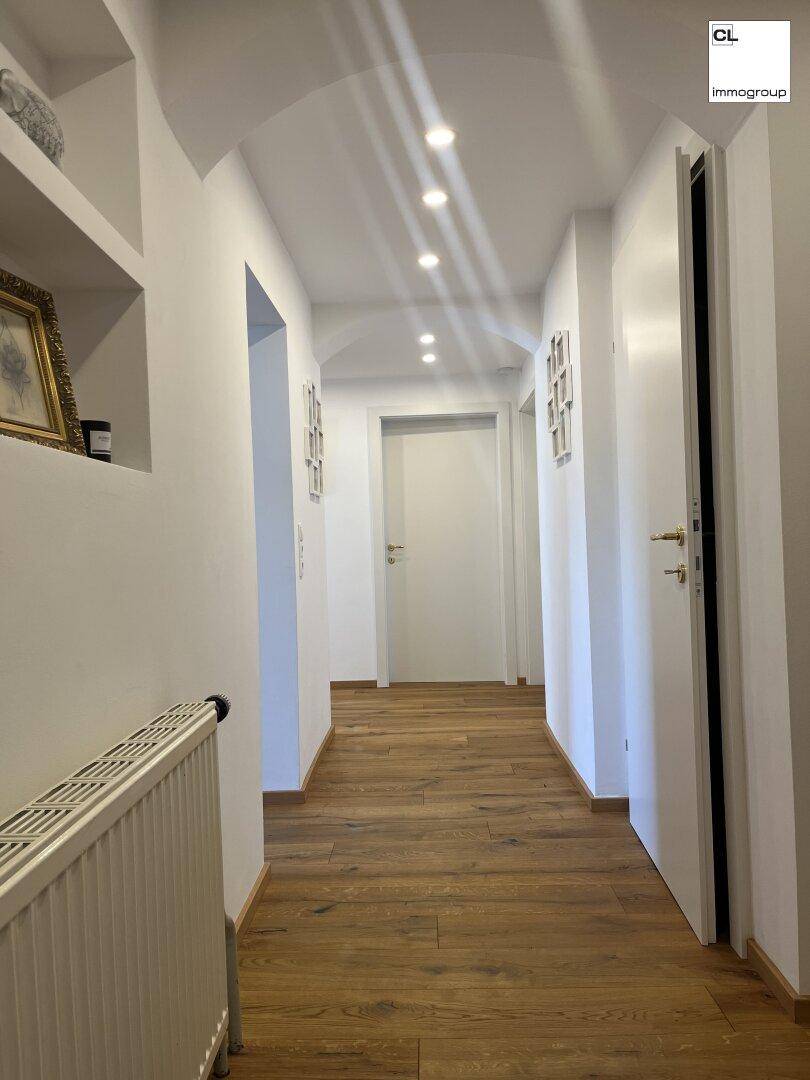 Heller Flur mit Holzboden, gewölbter Decke und integrierter Beleuchtung, führt zu weiteren Räumen.