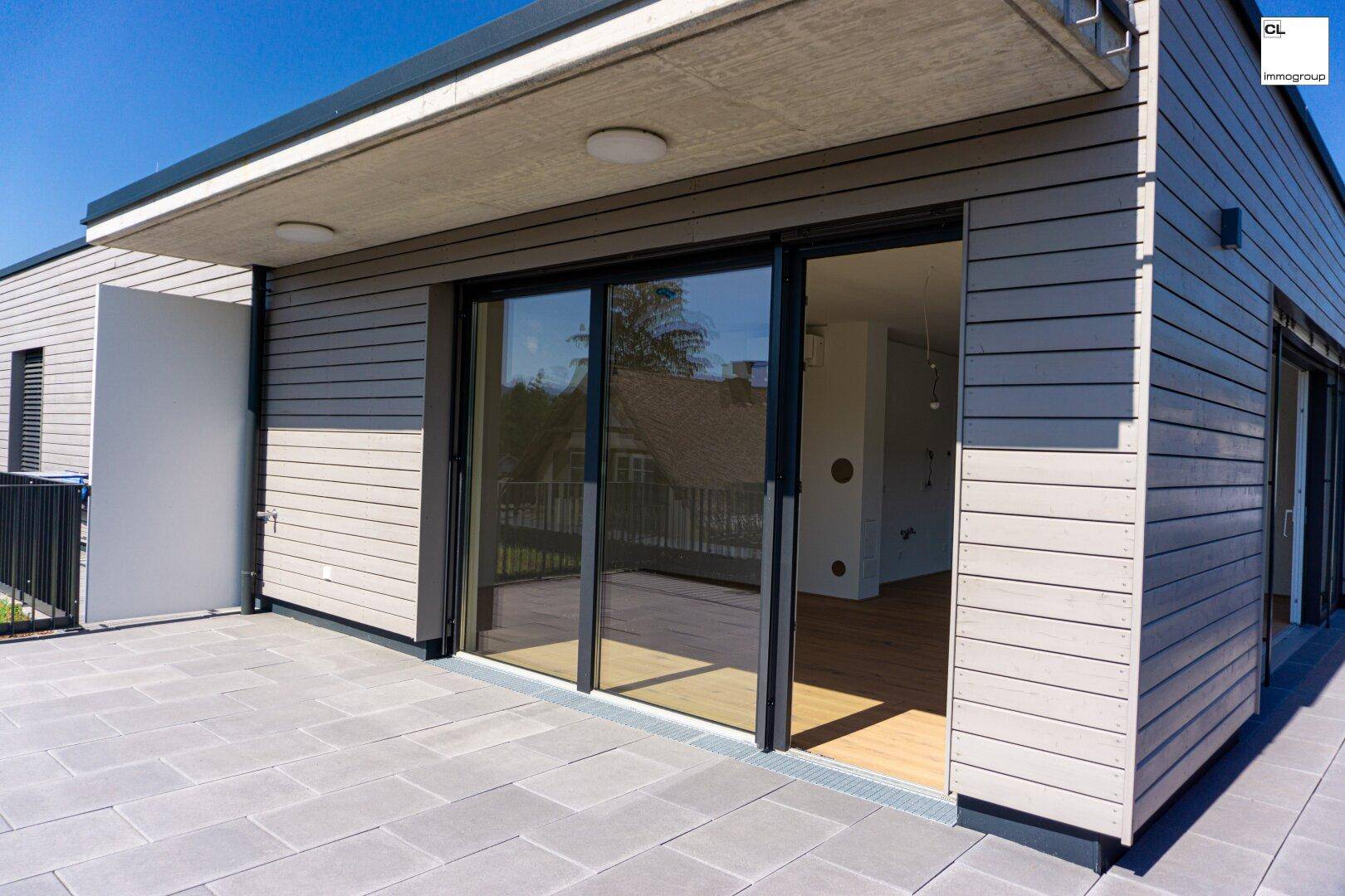 Große gepflasterte Terrasse mit modernen Schiebetüren, die in einen hellen Innenraum führen.