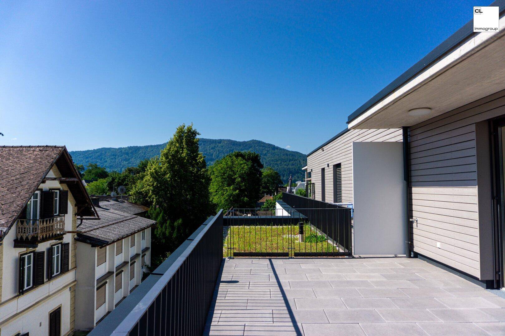 Weitläufige Terrasse mit Blick auf die umliegende Bebauung und grüne Hügel in der Ferne.