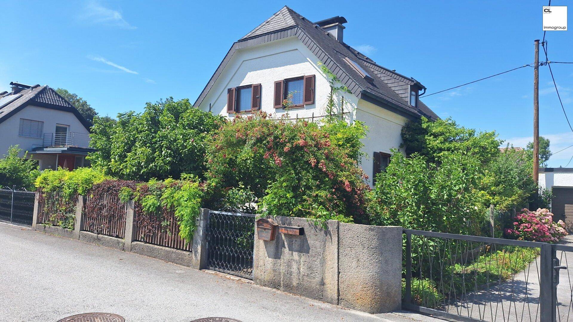 Charmantes Einfamilienhaus von der Straße aus gesehen, umgeben von einem gepflegten Garten und Zaun.