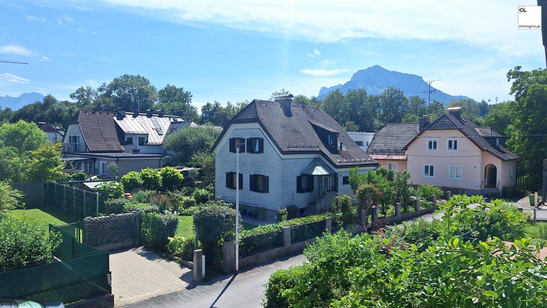 Weitläufiger Blick auf eine gepflegte Wohngegend mit verschiedenen Häusern und majestätischem Bergpanorama.