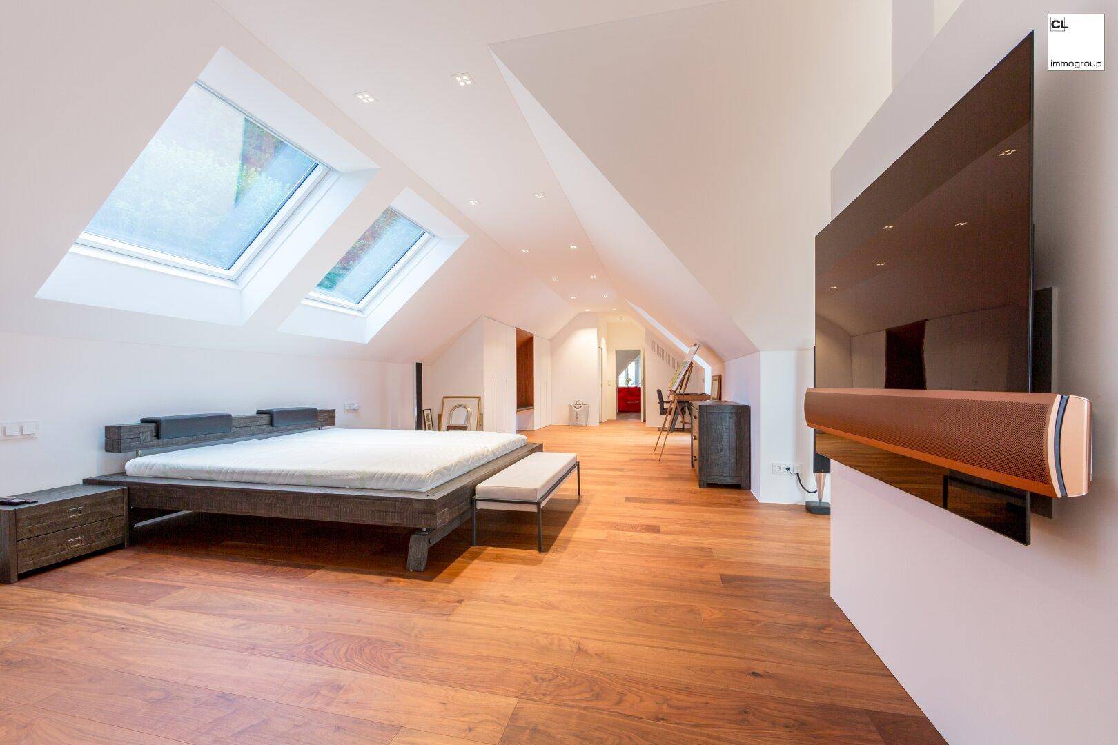Helles Schlafzimmer im Dachgeschoss mit Holzboden, modernen Möbeln und großen Dachfenstern.