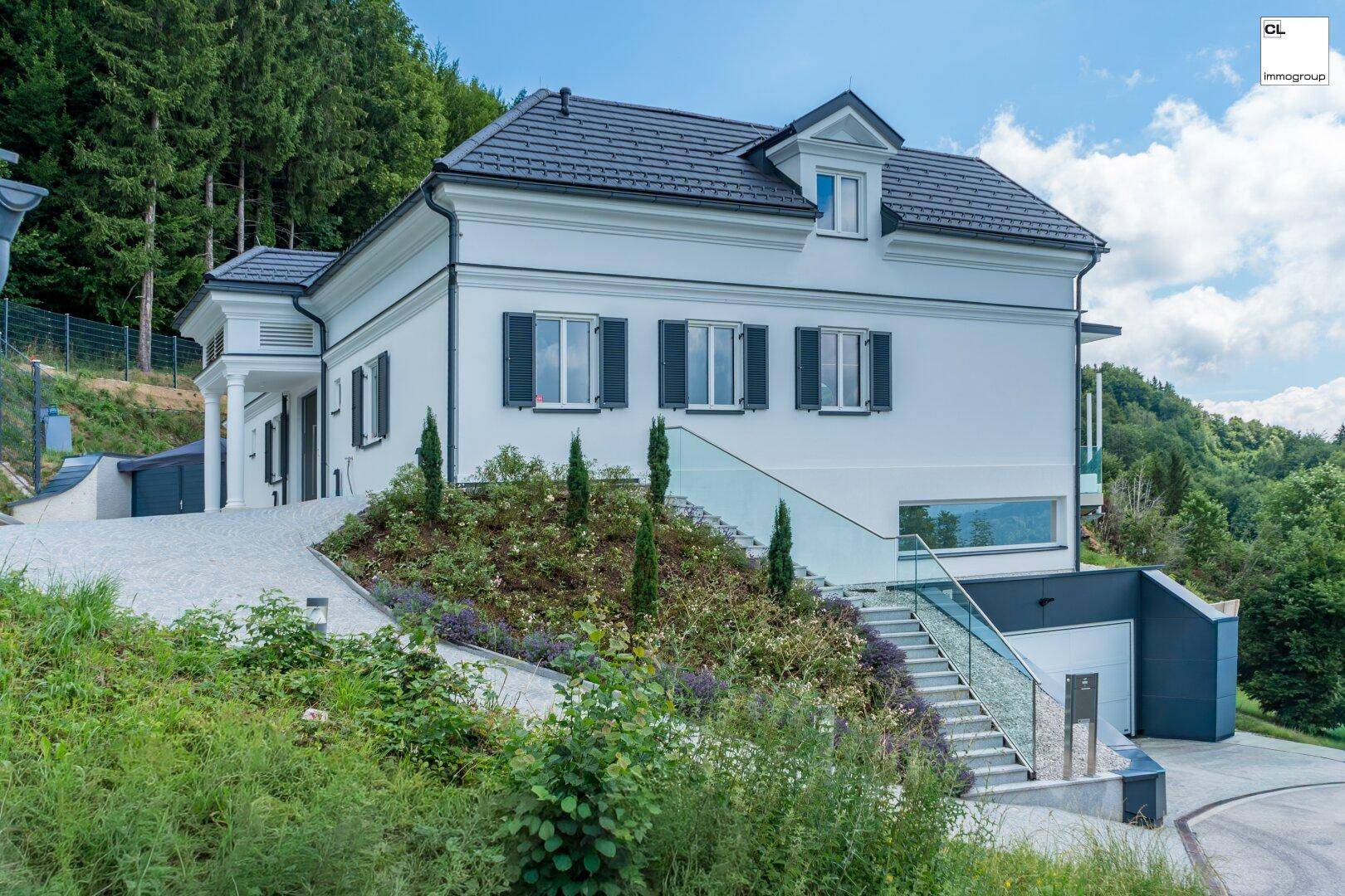 Elegantes weißes Haus mit klassischer Architektur, dunklem Dach und modernem Zugangsbereich.