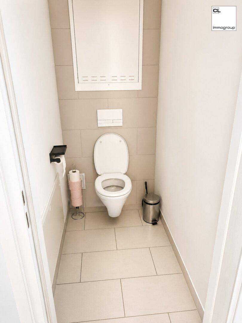 Saubere Gästetoilette mit Wand-WC und hellen Fliesen in einem modernen Design, sehr gepflegt.