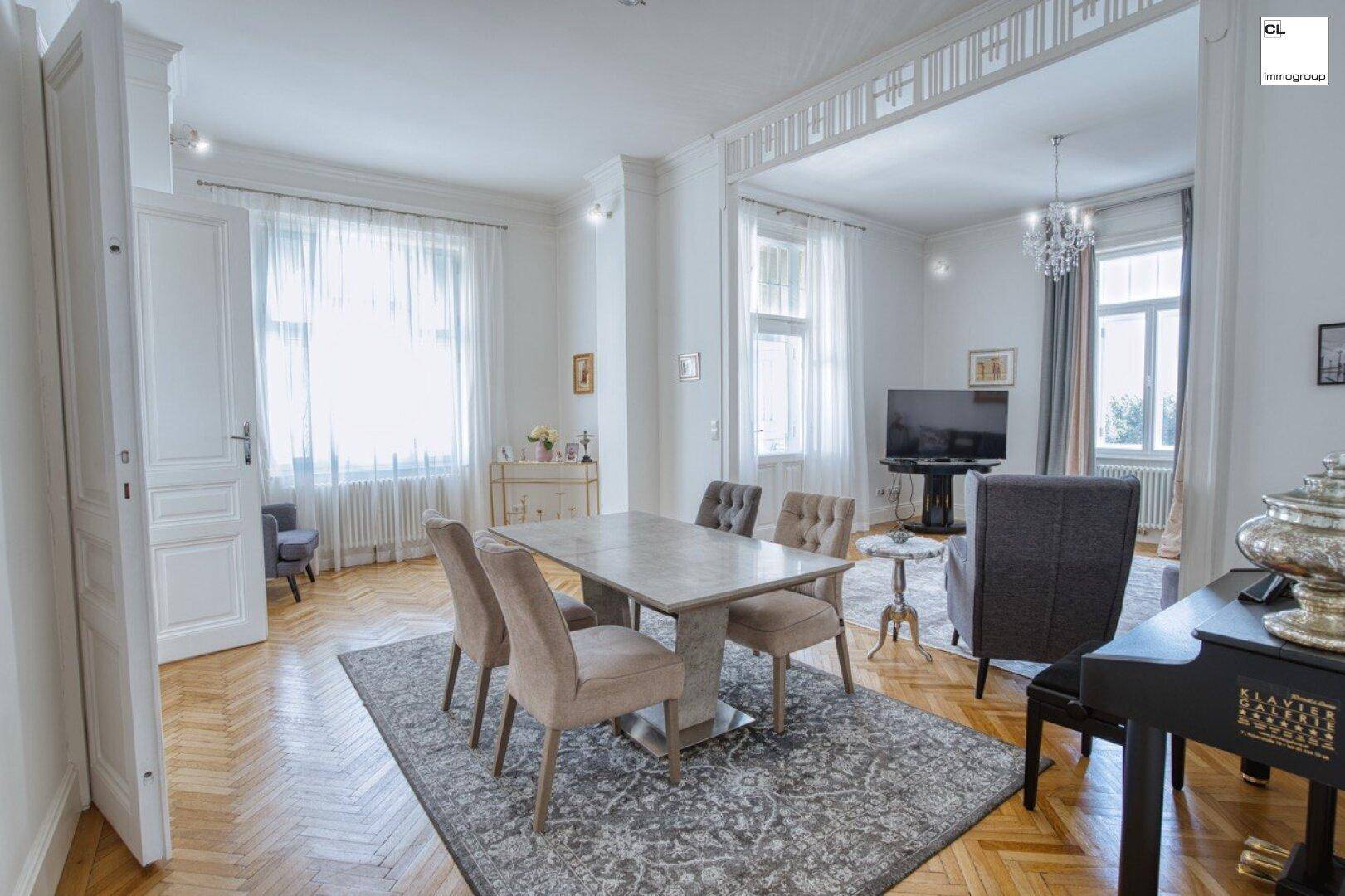 Geräumiger Wohn-Essbereich mit Fischgrätparkett, hohen Decken und eleganten Möbeln.
