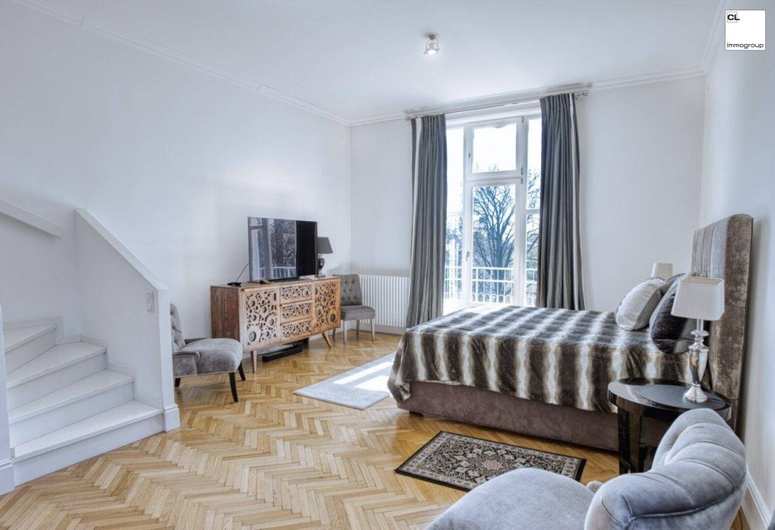 Helles Schlafzimmer mit großem Bett, Fernseher und Zugang zu einem französischen Balkon.