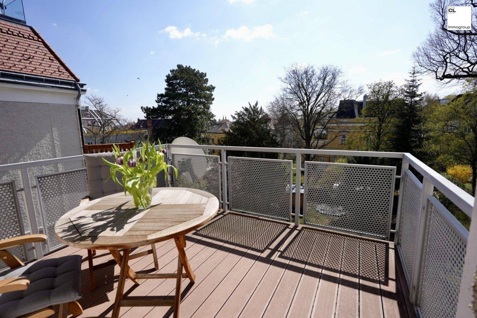 Sonniger Balkon mit Holzboden, Sitzgelegenheiten und Blick ins Grüne.