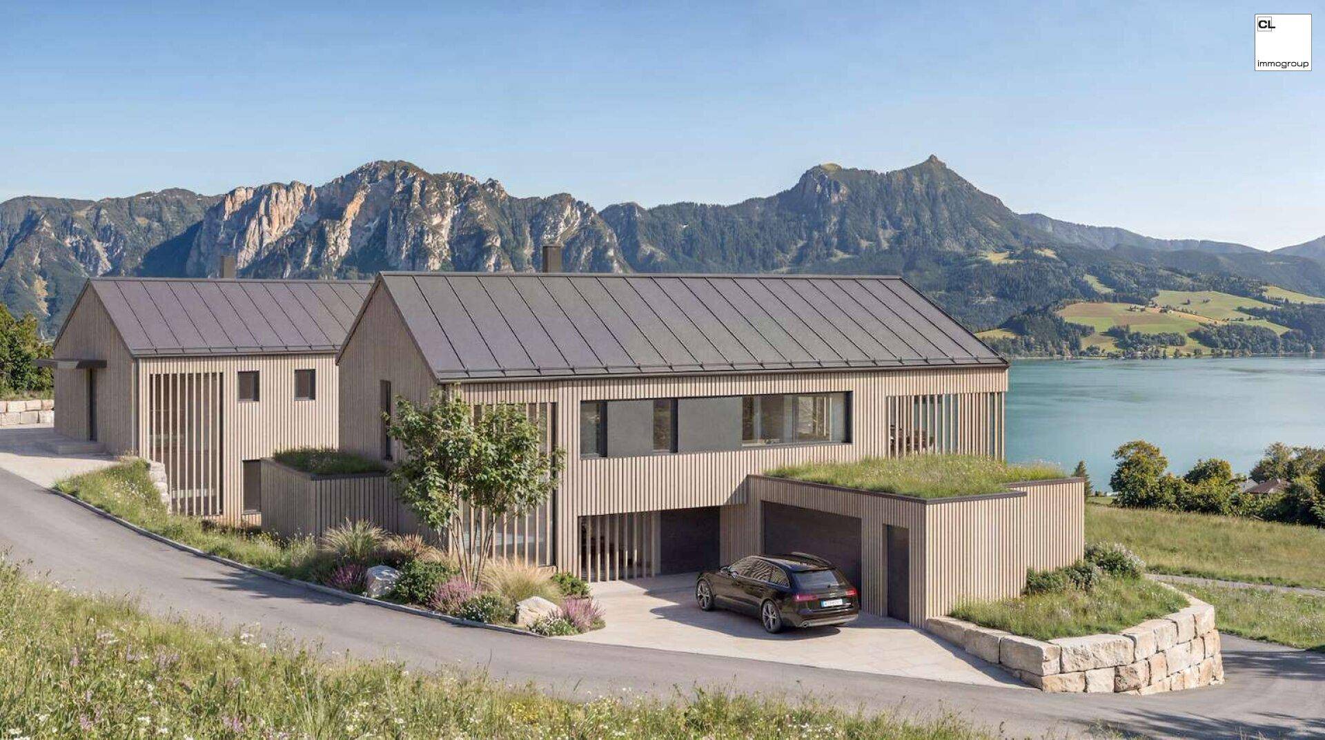 Modernes Haus mit Holzfassade und Gründach, eingebettet in eine malerische Berg- und Seenlandschaft.