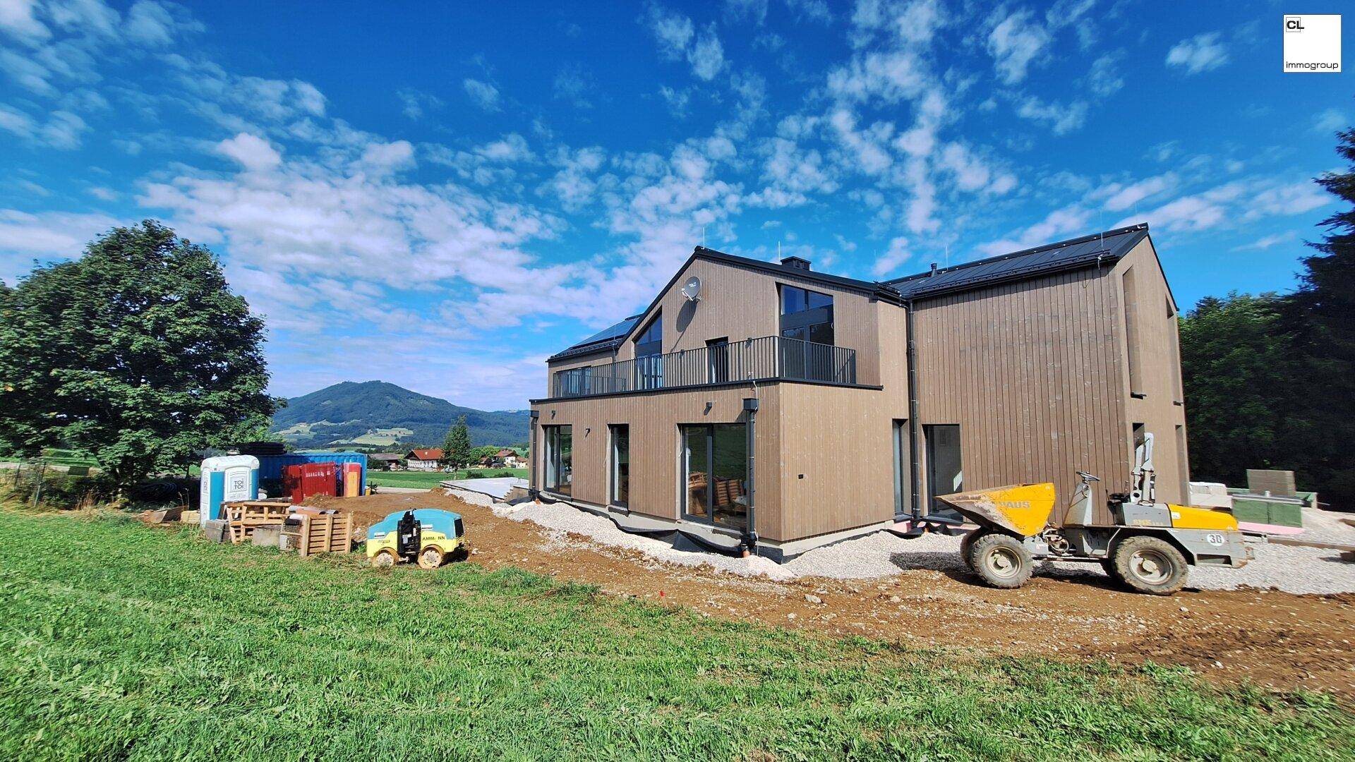 Neubau eines modernen Hauses mit Holzverkleidung und weitem Blick über die grüne Landschaft.