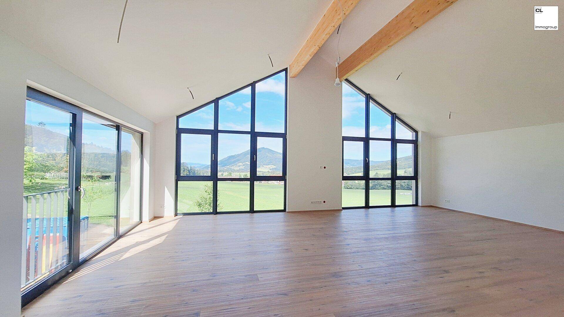 Heller Wohnbereich mit hohen Decken, Holzboden und beeindruckendem Panoramablick durch große Fenster.