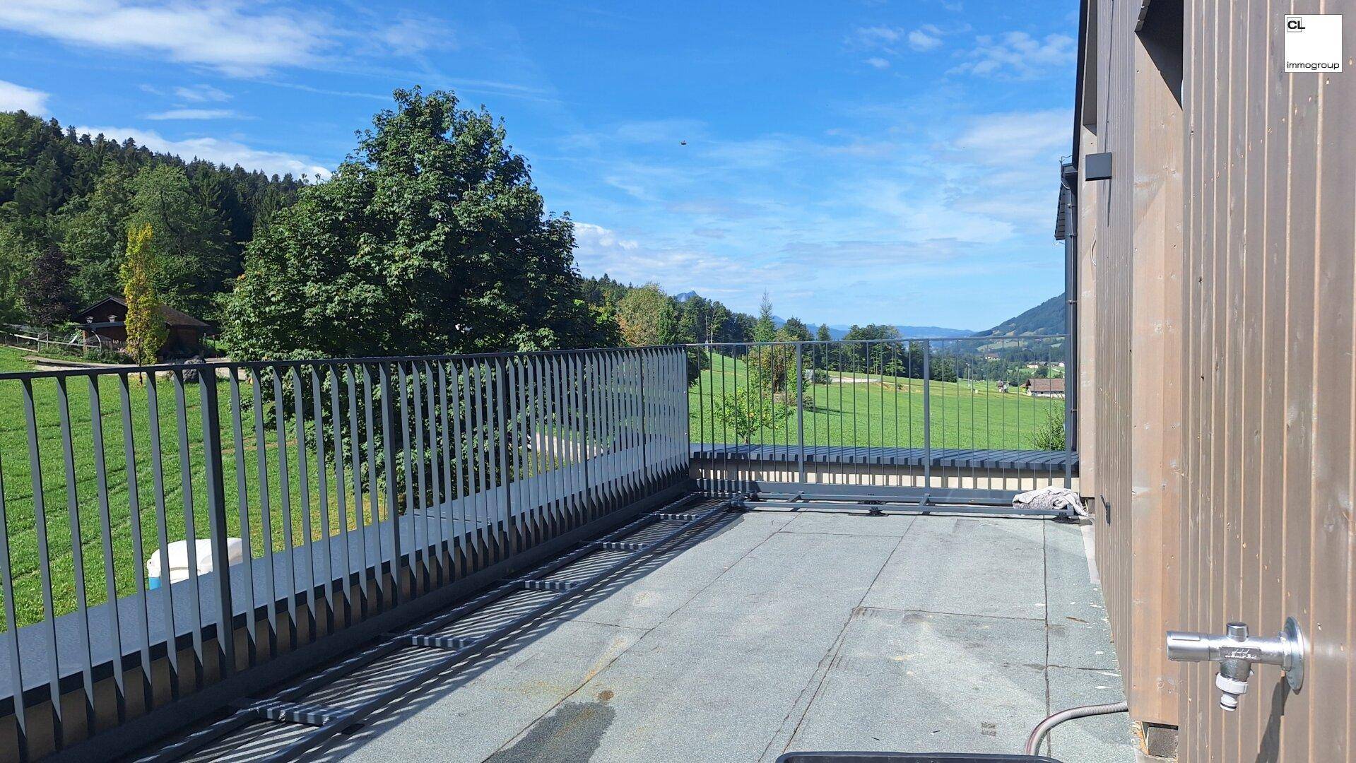 Große Terrasse mit Metallgeländer und weitem Blick über die grüne Landschaft.