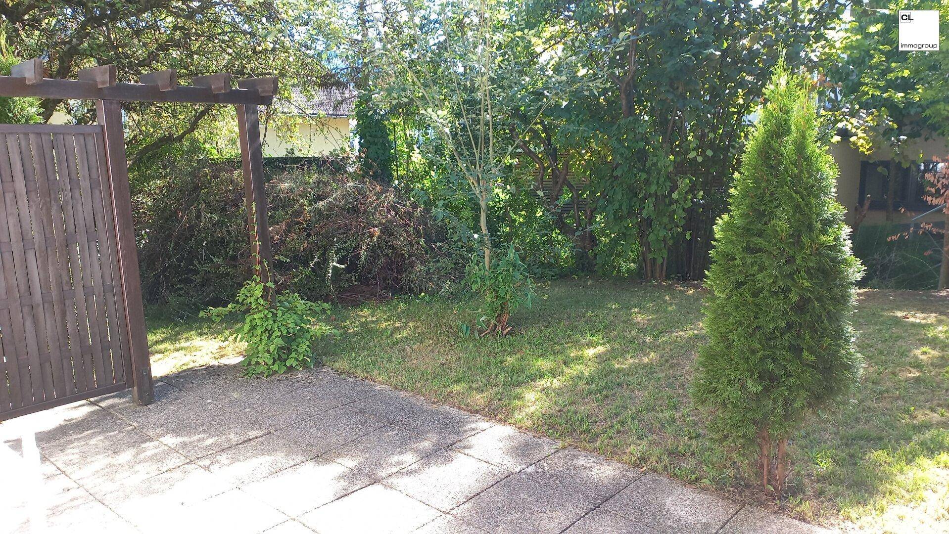 Ruhiger Gartenbereich mit gepflastertem Weg und üppiger Vegetation, ideal für Erholung im Freien.