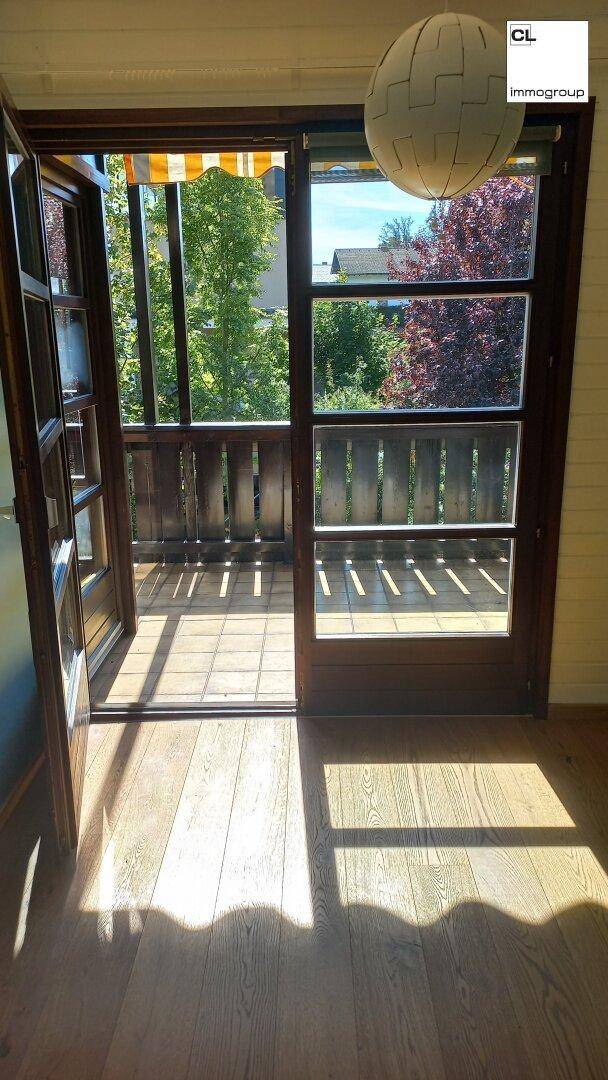 Helles Zimmer mit Holzboden und Zugang zu einem Balkon, bietet viel Tageslicht und frische Luft.