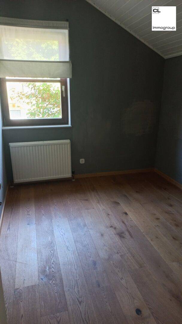 Schlafzimmer im Dachgeschoss mit Holzboden und Fenster, bietet eine gemütliche Atmosphäre und viel Licht.
