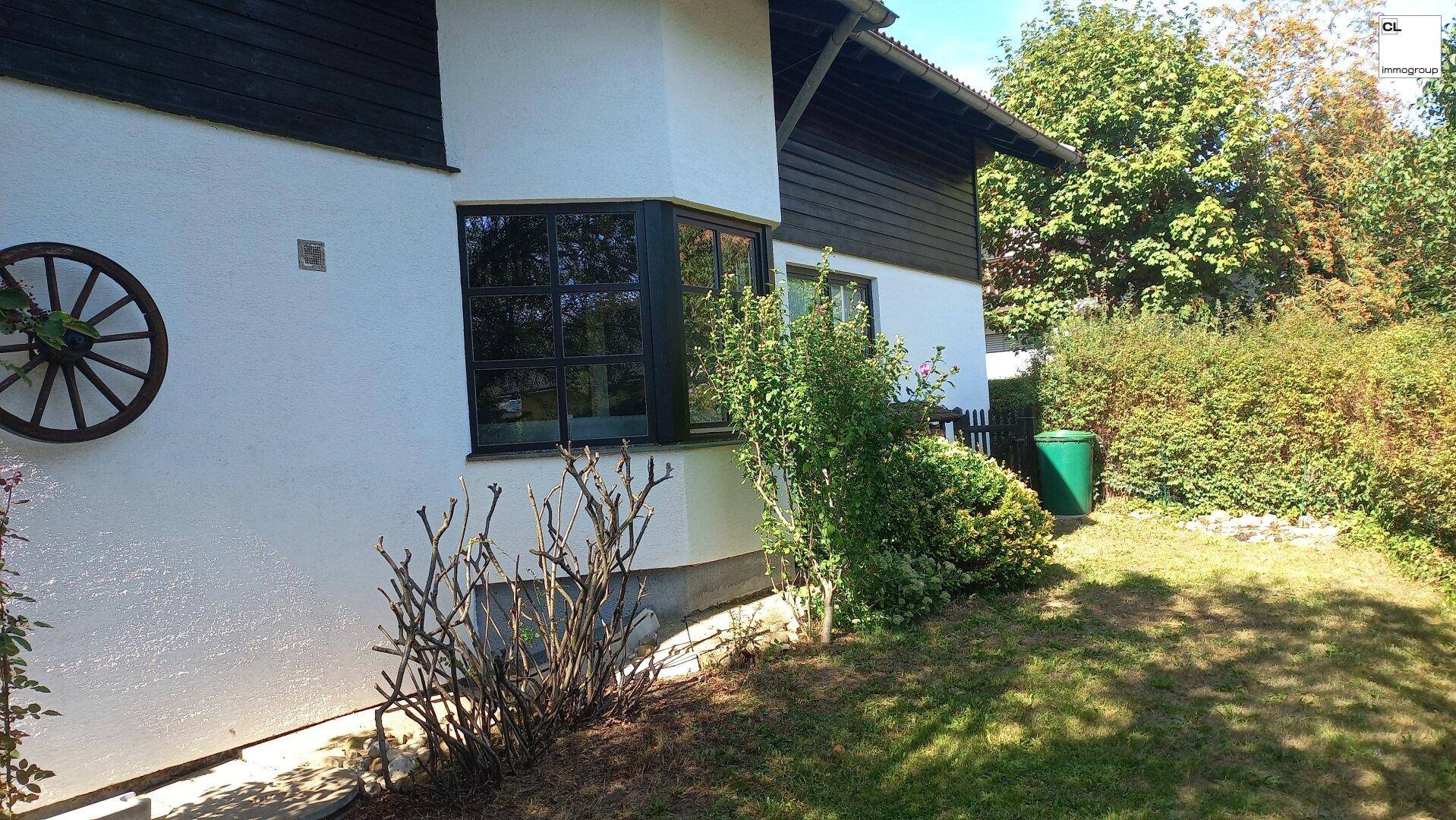 Gepflegter Gartenbereich neben dem Haus mit üppiger Bepflanzung und viel natürlichem Grün.