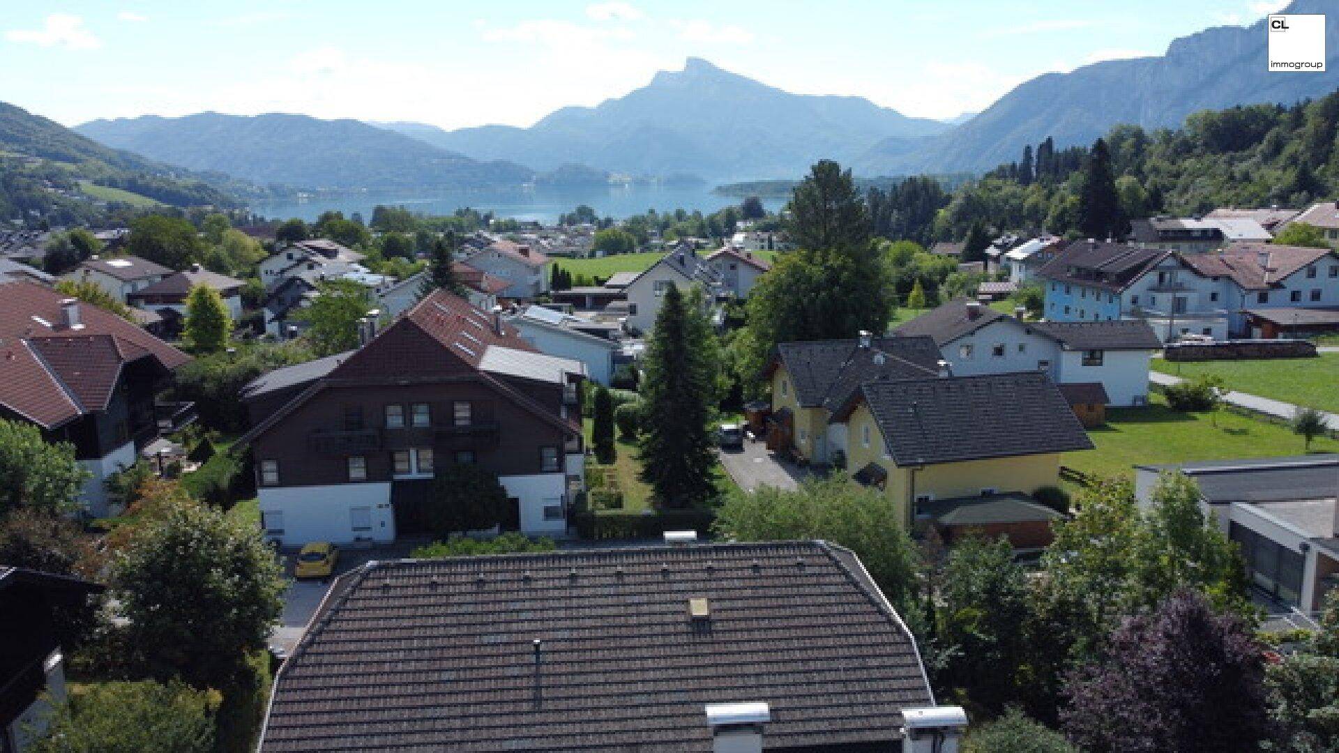 Luftaufnahme einer Wohnsiedlung mit Blick auf einen See und die umliegenden Berge.