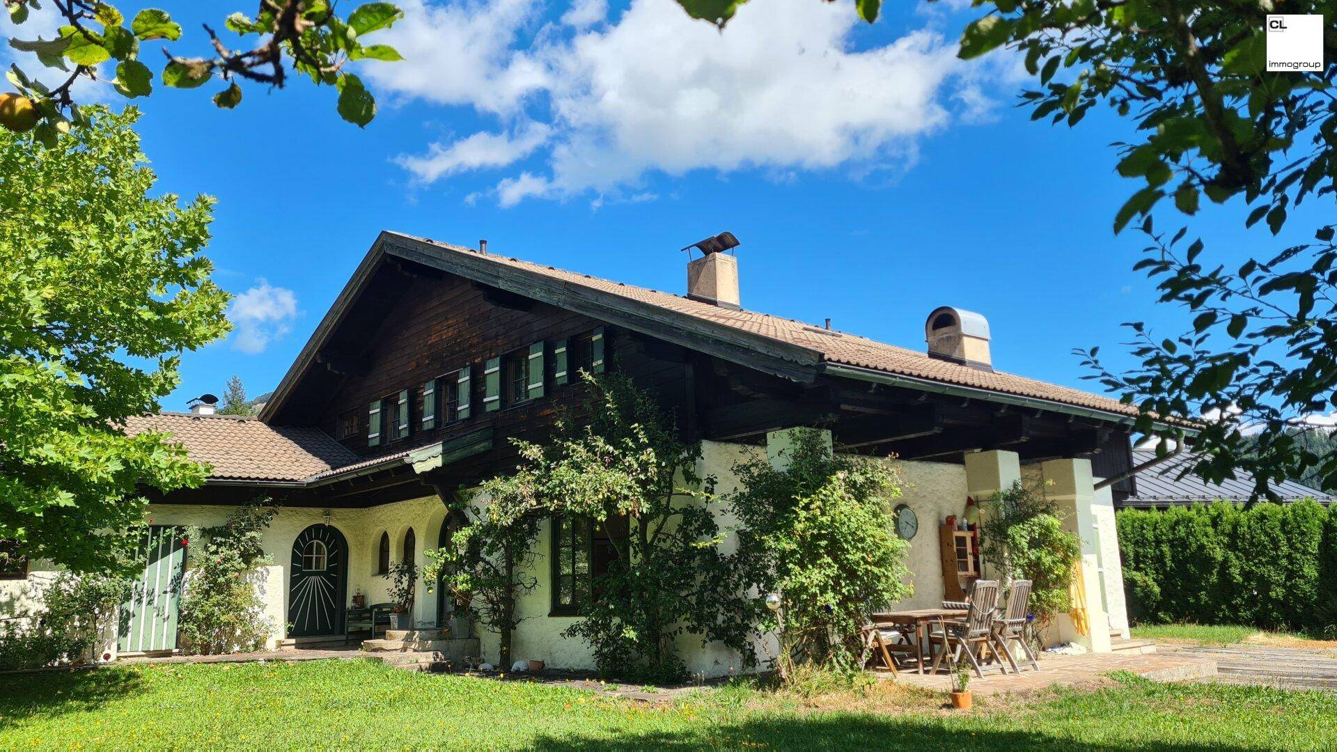 Traditionelles Haus im Alpenstil mit gepflegtem Garten und einer kleinen Terrasse für Mahlzeiten im Freien.