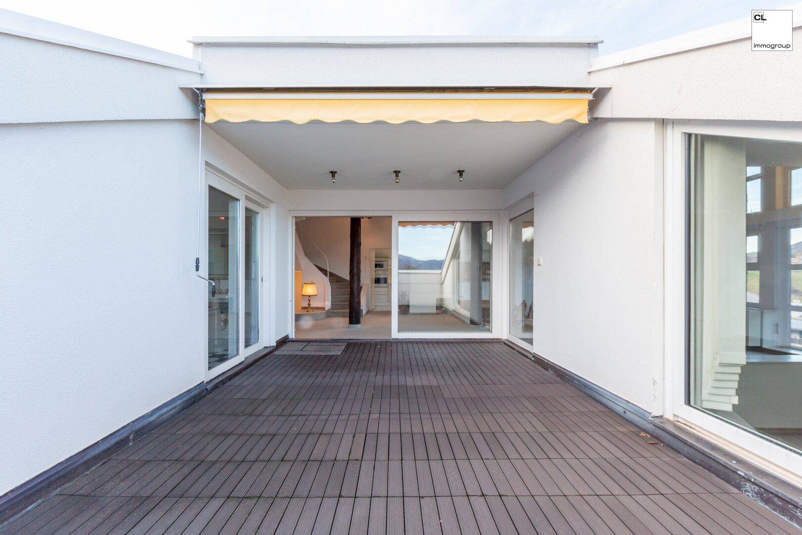 Geräumige Terrasse mit Holzboden und Markise, ideal für entspannte Stunden im Freien.