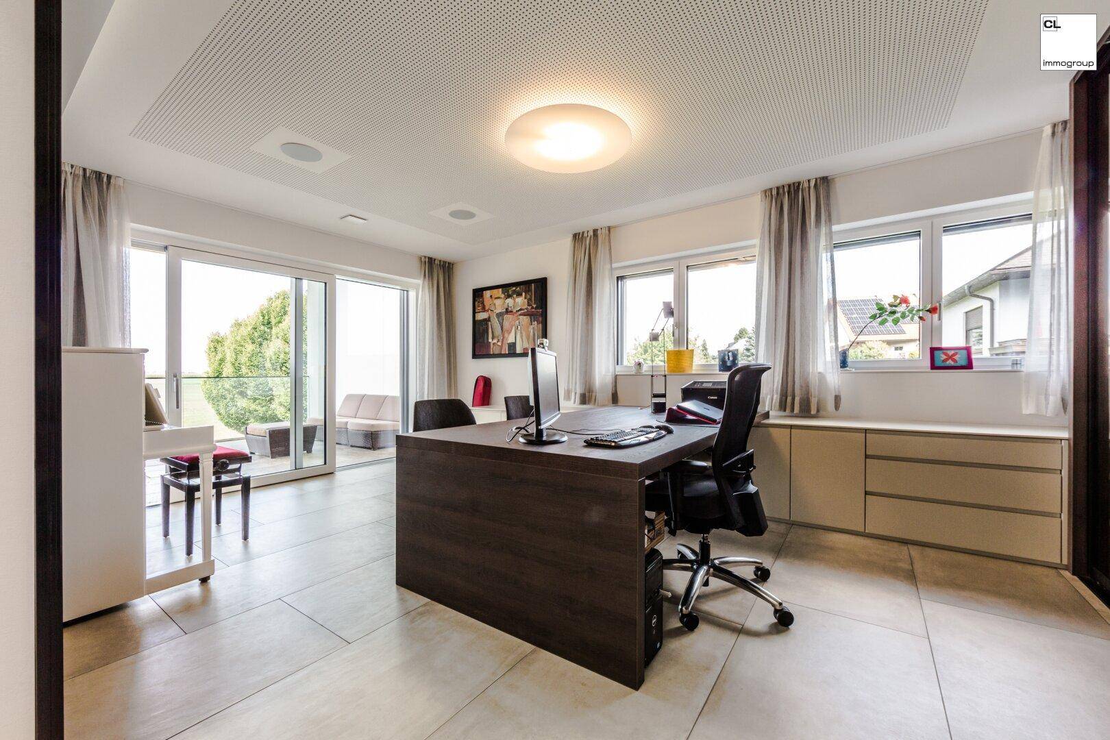 Helles Büro mit großem Schreibtisch und Zugang zu einer Außenterrasse.