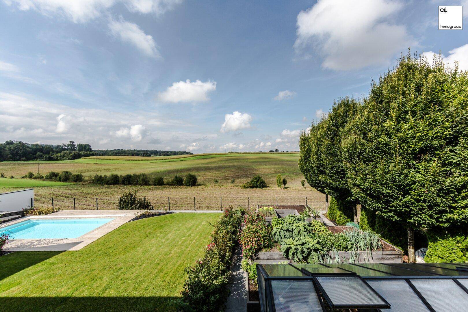 Weitläufiger Garten mit Swimmingpool, Rasenfläche, Gewächshaus und Panoramablick auf die Landschaft.